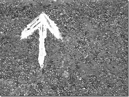 White paint arrow on asphalt bw